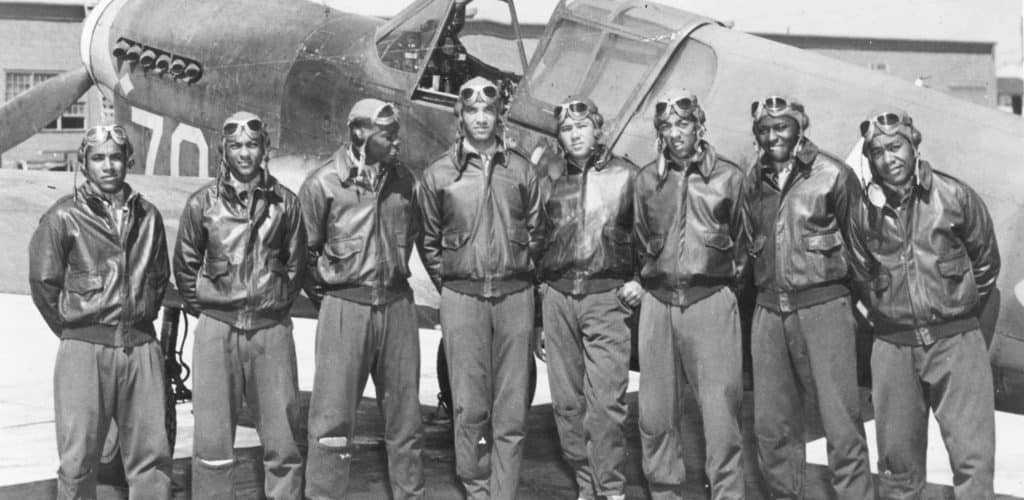 Eight Tuskegee Airmen in front of a P 40 fighter aircraft