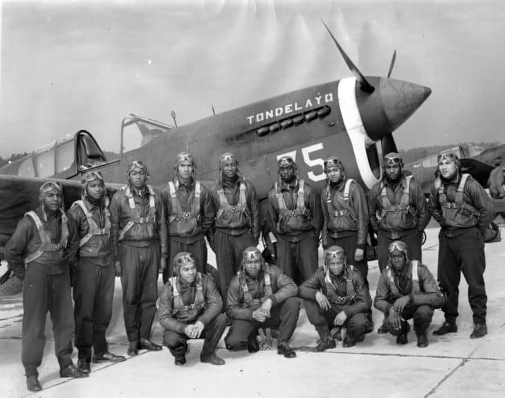 Thirteen members of Tuskegee Airmen class 43C posing in front of an airplane